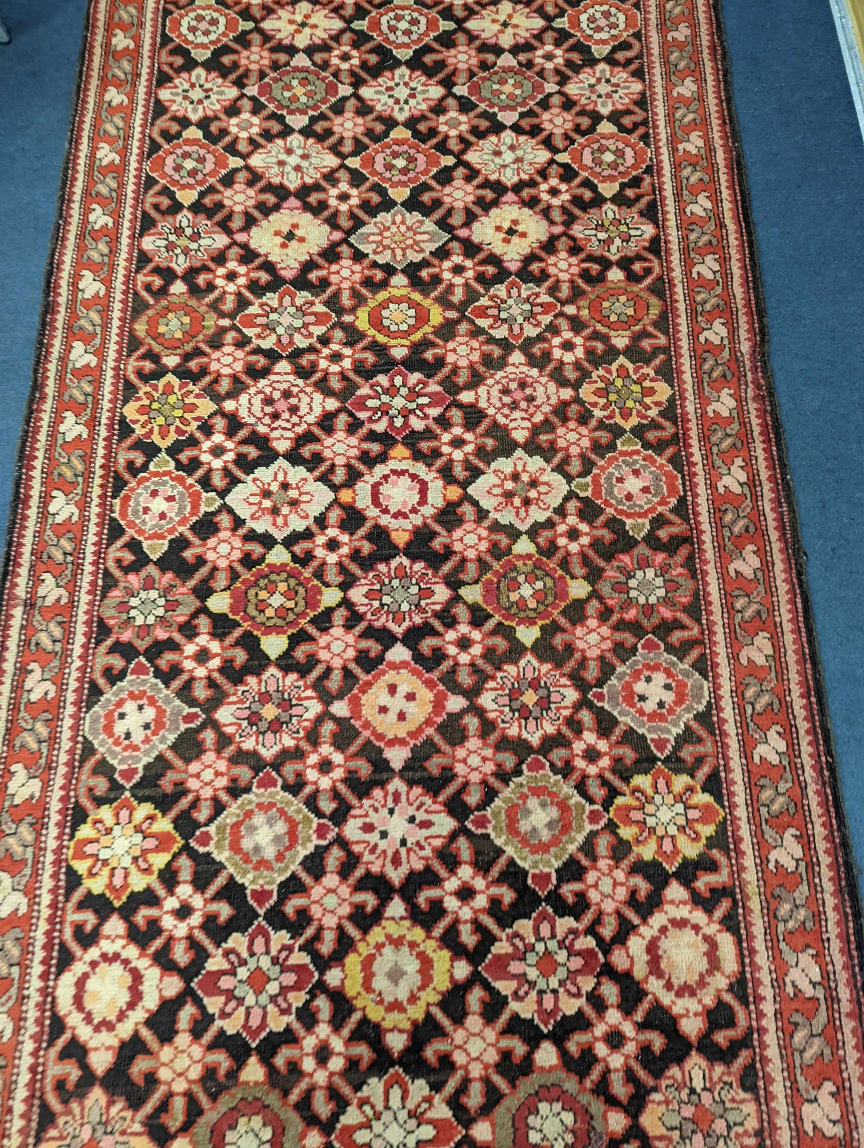 A North West Persian runner woven with rows of floral motifs, 575 x 110cm